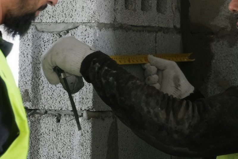 Přeměřování zdiva svinovacím metrem na stavbě